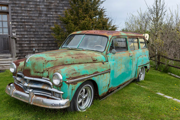 side view of an old rusting car with a surf board out on the back