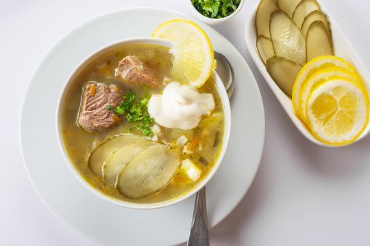 Soup Rassolnik with pickled cucumber, lemon and sour cream on a white background. Russian cuisine. Close up. Selective focus. For the menu.
