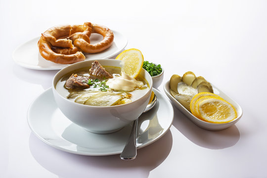 Soup Rassolnik with pickled cucumber, lemon and sour cream on a white background. Russian cuisine. Close up. Selective focus. For the menu.
