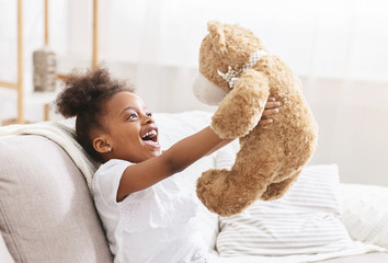 Cute african american child hugging teddy bear and smiling