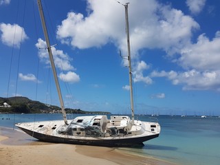 Shipwreck of an large sailboat on a sandy beach.