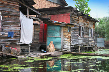 Traditional kashmiri view,  old wooden houses on stilts, boat, Dal lake with duckweed, hanging...