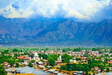 Beautiful city scape, traditional kashmiri houses and sikh temple in green valley against the background of colorful mountain range and sky in Srinagar, Himalayas, Jammu & Kashmir, India