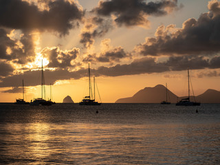 Fototapeta premium Sailboats in tropical laggon with the sunsetting behind the clouds and masts