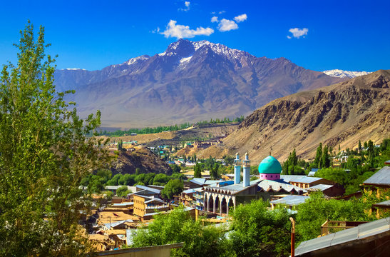 Beautiful city scape - traditional houses and mosque with emerald green cupola against the background of mountain range and blue sky in Kargil, Himalayas, Ladakh, Jammu & Kashmir, Northern India