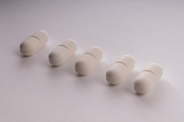 Five light pills in a row on a white background