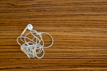 Tangled headphones cable on a wooden desk, with copyspace