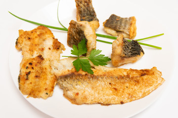 Tasty food, nutrition, kitchen and culinary concept: closeup pieces of fried, baked, golden and tasty fish on a white plate.