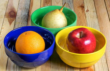 fresh fruit in multicolored plates, delicious tasty and healthy food vegetarian food Apple, pear and orange