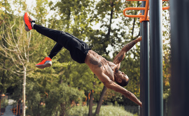 Afro Man Doing Stand Abs Exercise On Bar Outdoors