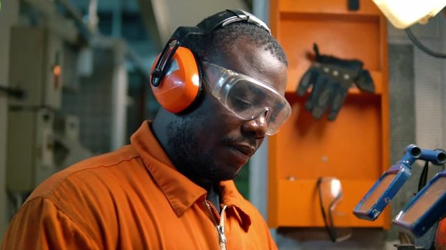 African marine engineer officer in engine control room ECR. He works in workshop with equipment