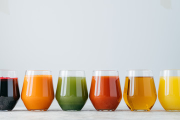 Vartiety of oranganic drink in glasses. Assorted multicolored juice in jar standing at row against...