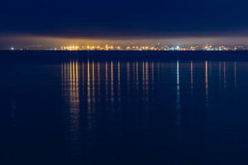 Fototapeta na wymiar night city lights in the reflection on the beach