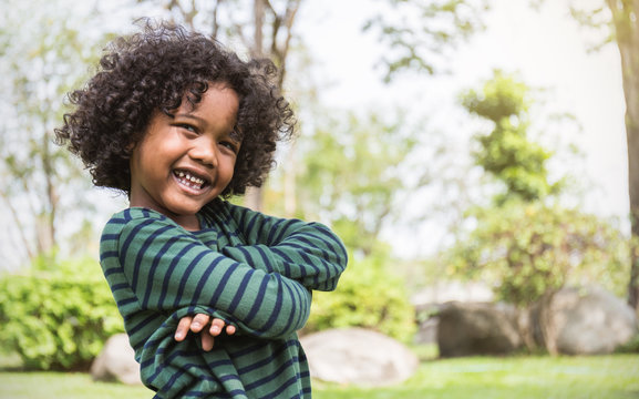 Fun In The Spring Park. Portrait Of Young Happy Black Boy Stand On Green Grass Background. Education Back To School Spend Leisure Time In Nature Forest Concept