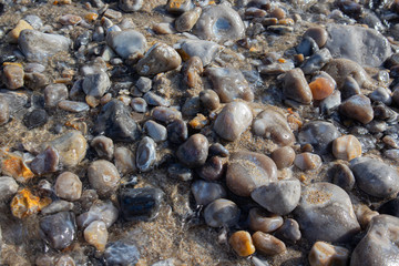 Colorful pebble stones under sea water. Beach scene. Textured background.