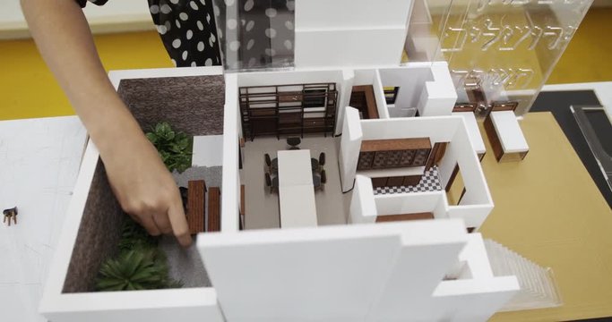 Architecture design studio with plastic and wood model and mock-up of new building. View of miniature house interior with furniture