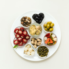 Italian traditional pickles on a plate. tuna stuffed peppers, artichokes in oil, olives, mushrooms, capers. copy space.