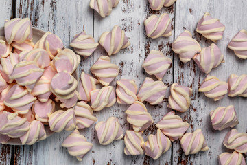 Pink marshmallows with yellow curls, on light wooden background. Poured from the plate