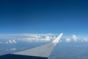 Fototapeta na wymiar In-flight view on aircraft wing with blue sky above clouds