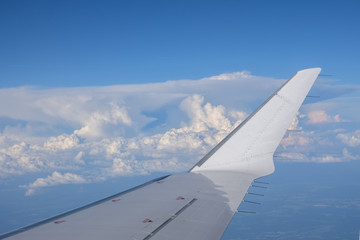 Fototapeta na wymiar In-flight view on aircraft winglet with blue sky above clouds