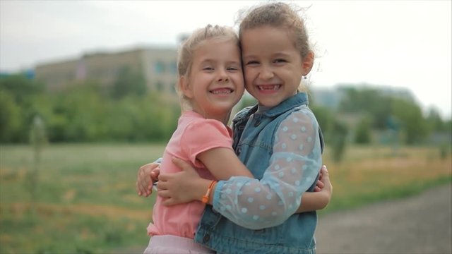 Two smiling, curly, cute sisters baby-girls hug tightly each other. Happy childhood, positive emotions, true feelings.