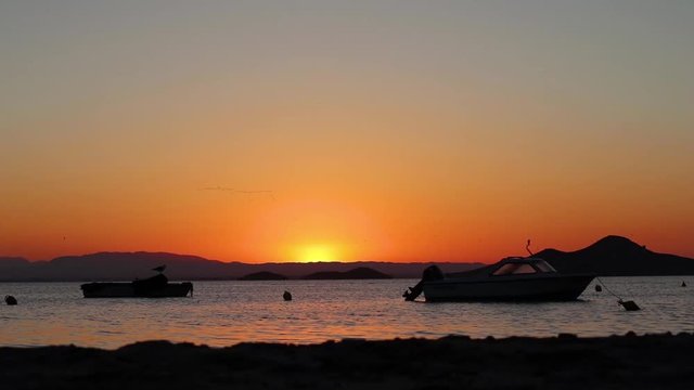 Stunning sunset at sea with docked boats and seagulls. Mar Menor in Murcia, Spain.