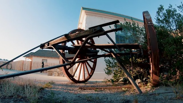Old rusty wagon trailer wheels sitting on gravel, Low Angle Dolly In