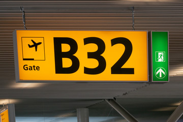 Yellow illuminated airport gate number sign with emergency exit indicator