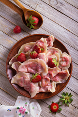 Dumplings, filled with strawberries. Varenyky, vareniki, pierogi, pyrohy - dumplings with filling. View from above, top studio shot
