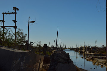 Calle inundada, ruinas y postes de iluminación de un pueblo abandonado