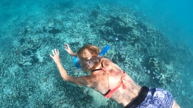 woman swims underwater of Cocos Island, Seychelles. Girl with fishes in the Indian Ocean. Tropical destination holiday and travel lifestyle with watersport activity.