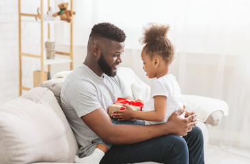 African american man sitting with his little daughter with gift box