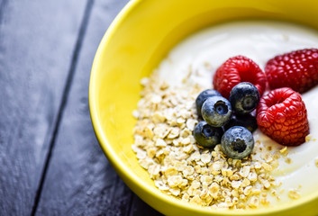 Morning breakfast with tasty berries all on a dark wooden table.