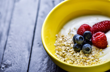 Morning breakfast with tasty berries all on a dark wooden table.