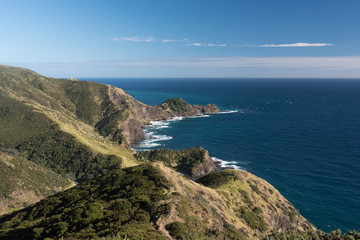 Elevated view of the rocky, Pacific coast of Cape Reinga, with the lighthouse visible in the background. Northland, New Zealand.