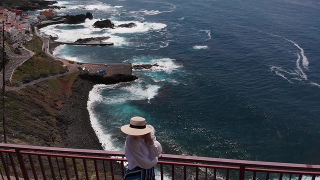 Aerial view of a woman overlooking the turquoise ocean with big waves, El Pris, Tenerife, Canary Islands, Spain