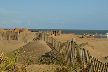 dunas de arenas cerca del mar con una valla