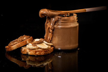 closeup creamy peanut butter in glass jar and on crackers