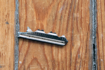 Broken key on old wooden background. The tongue is a broken rusty key from door lock.