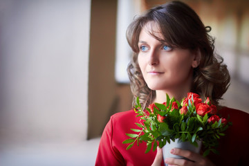 The teacher in the school hallway at the prom. A young woman looks out the window at a school holiday. The teacher holds a bouquet of flowers donated by students.