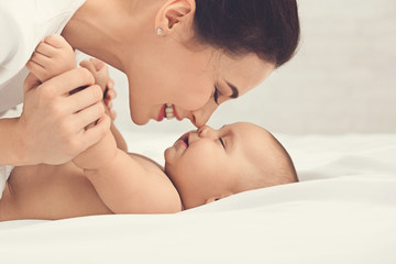 Mother and baby touching noses in bed