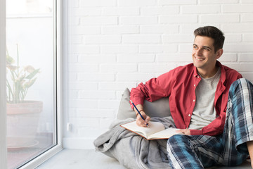 young man with notepad or book at home