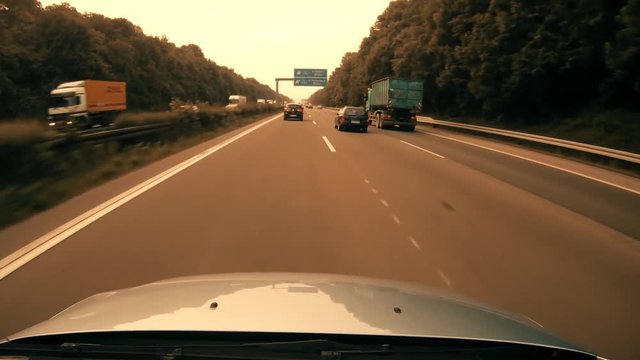 A highly stylized clip of a car speeding down the highway on the German autobahn. Highway dashcam warm grade.