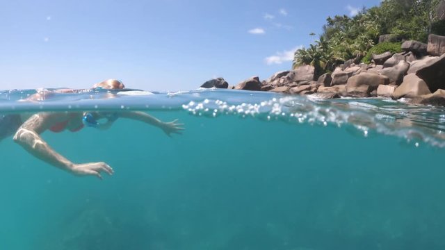 split view of female in wetsuit apnea at Seychelles, Indian Ocean. Travel lifestyle watersport activity. Young caucasian woman snorkeling in tropical turquoise sea. Woman free swims in coral reef
