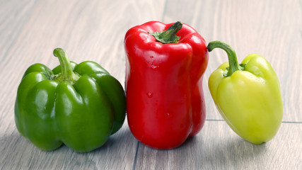 three colored sweet pepper on a wooden table