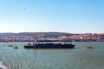 Lisbon, Portugal - Circa May 2019: Cargo ship on river with Lisbon city on the background