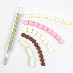 thermometer and medical pills on white background