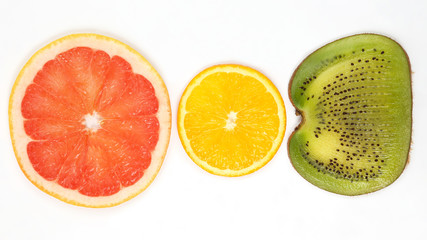 across sliced kiwi, orange and grapefruit on white background