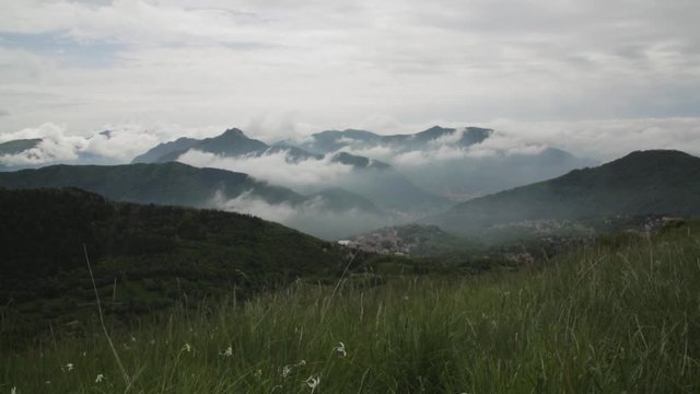 Mountain Colma with clouds sitting in between the mountain peaks and a small village at the bottom