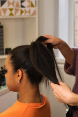 Fototapeta premium Hands professional female hairdresser doing evening hairstyle for her client. Hairdressing services. Сreating hairstyle. Hair styling process. Beauty industry.